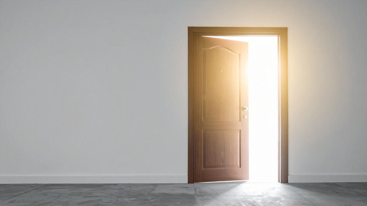 Open wooden door in a quiet, empty room with warm light pouring in, suggesting welcome, honesty, and a space where nothing needs to be performed.