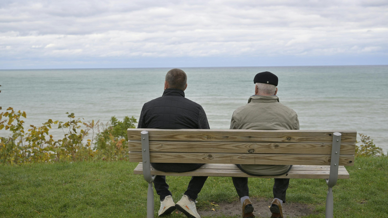 Two people sitting on a bench overlooking a lake, reflecting quietly together.