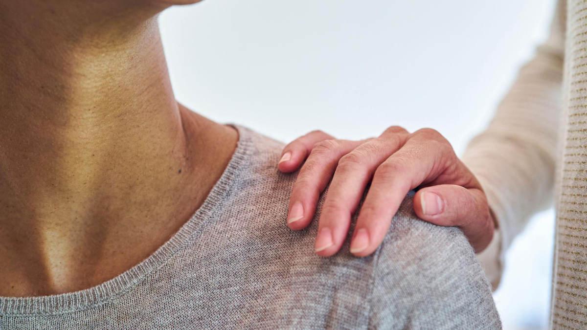 A gentle hand resting on someone’s shoulder, offering quiet comfort and support without words.
